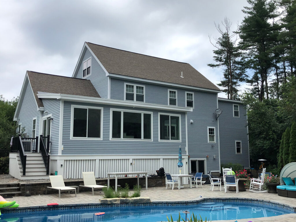 Exterior shot back of house inground pool with stone patio and new siding