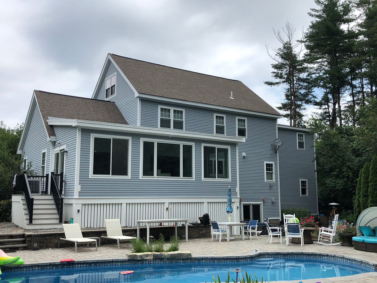 Exterior shot back of house inground pool with stone patio and new siding