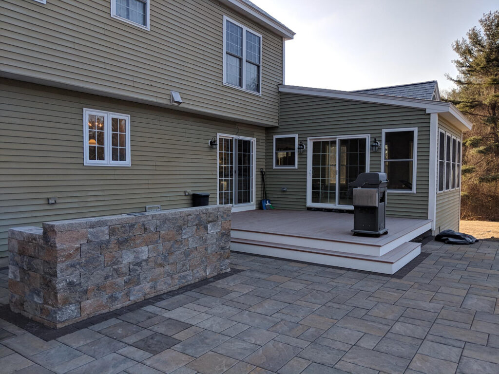 Stone patio with custom outdoor kitchen and new deck addition